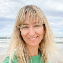 Woman with glasses and blonde hair standing on a beach